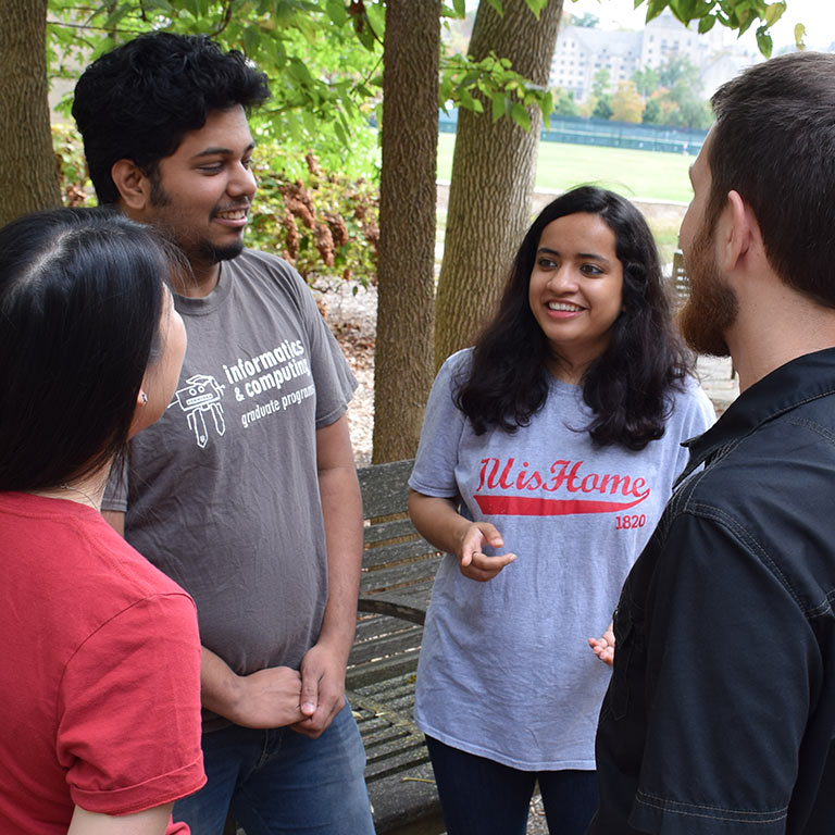 A group of data science students gather outside in a circle to talk. 