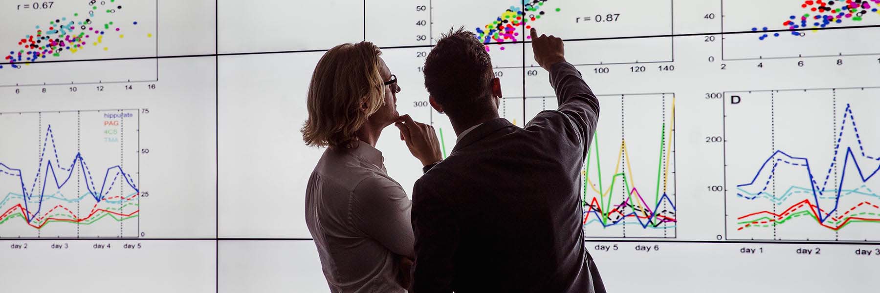 Two students point at a graph on the screens in the Visualization Lab in Luddy Hall.